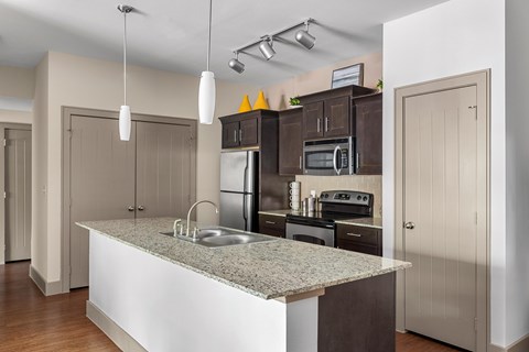 A kitchen with a granite countertop and stainless steel appliances.