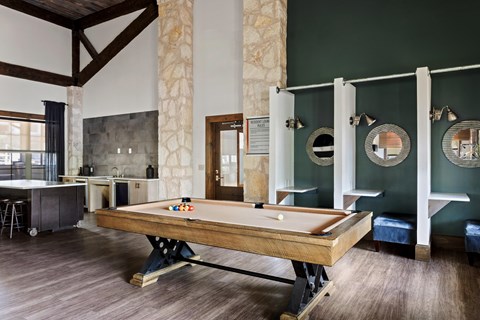 A pool table is in the middle of a room with a green wall.