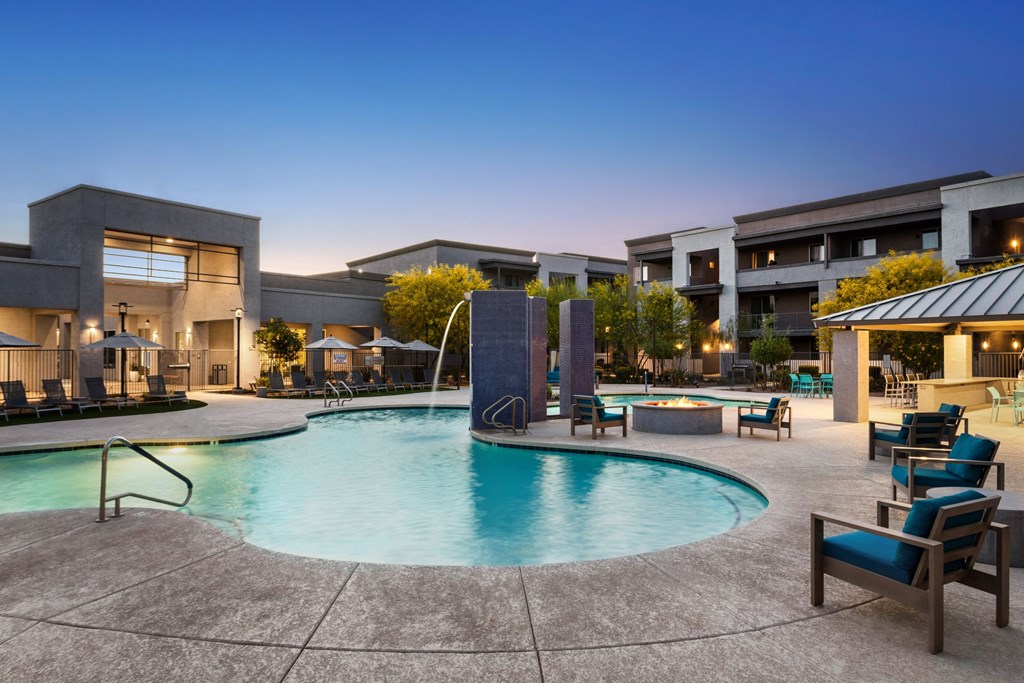 A swimming pool surrounded by lounge chairs and a building in the background.