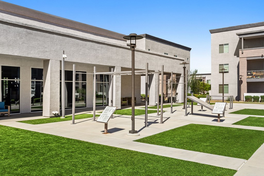 A modern building with a glass entrance and a green lawn in front.