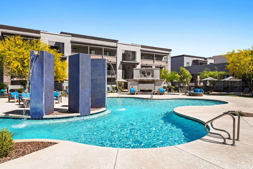 A swimming pool surrounded by a concrete patio and a metal railing.