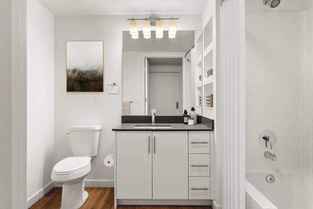 A white bathroom with a toilet, sink, and cabinet.