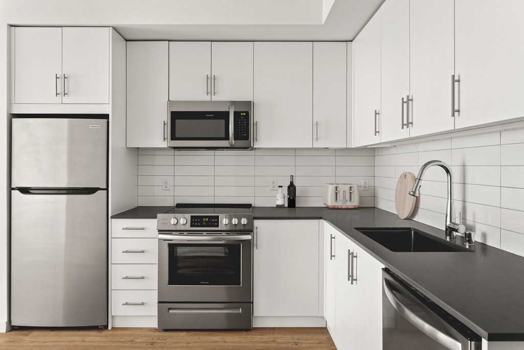 A modern kitchen with a stainless steel refrigerator, oven, and microwave.