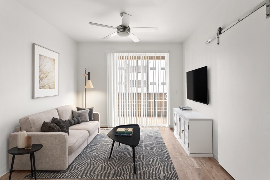 A living room with a couch, a table, a television, and a window with blinds.