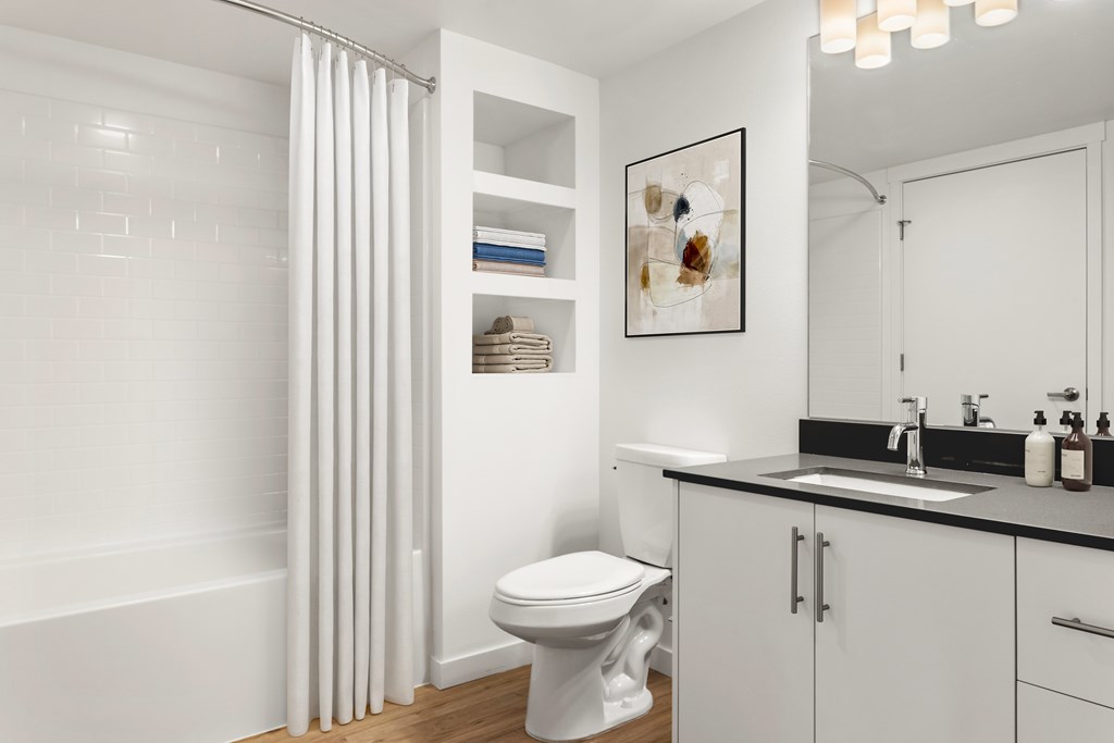 A white bathroom with a toilet, sink, and shower curtain.