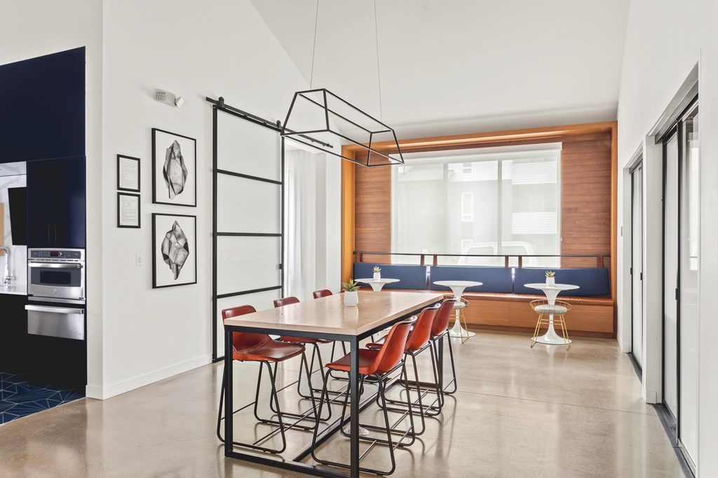 A modern dining room with a long table and chairs.