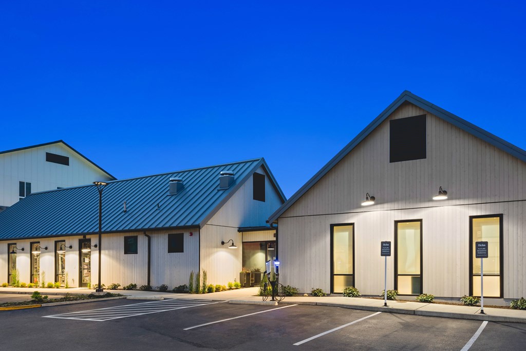 A building with a blue roof and white walls with a parking lot in front.