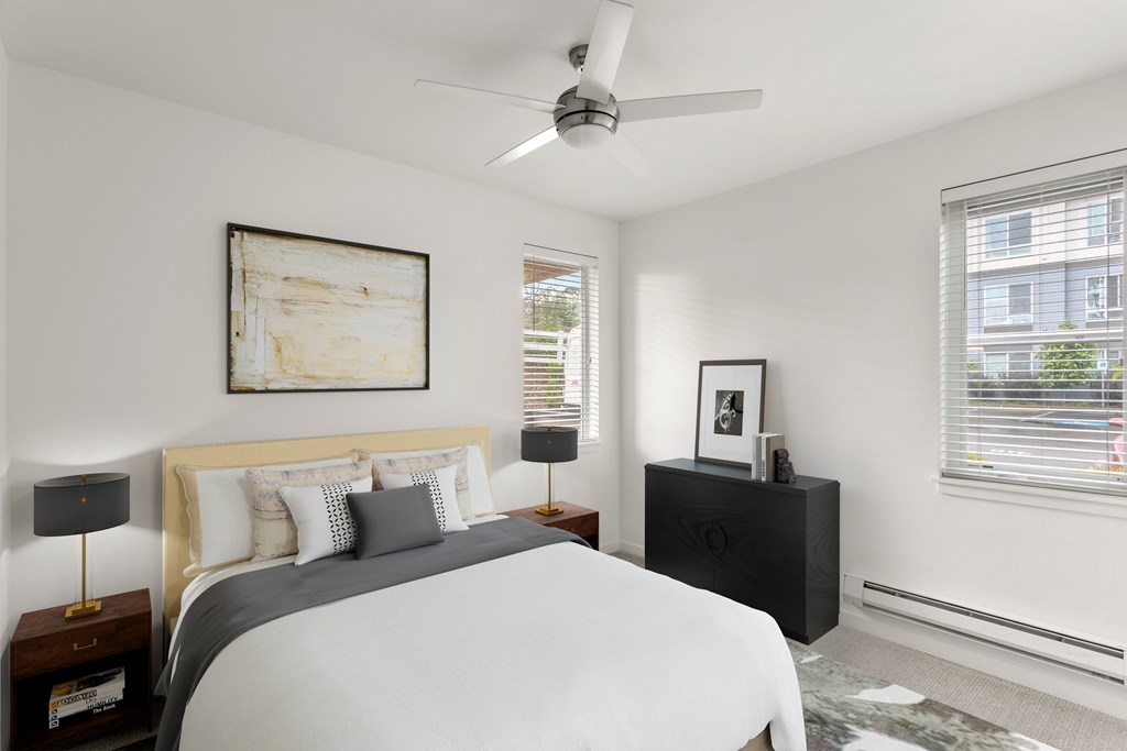 A bedroom with a bed, nightstand, and a painting on the wall.