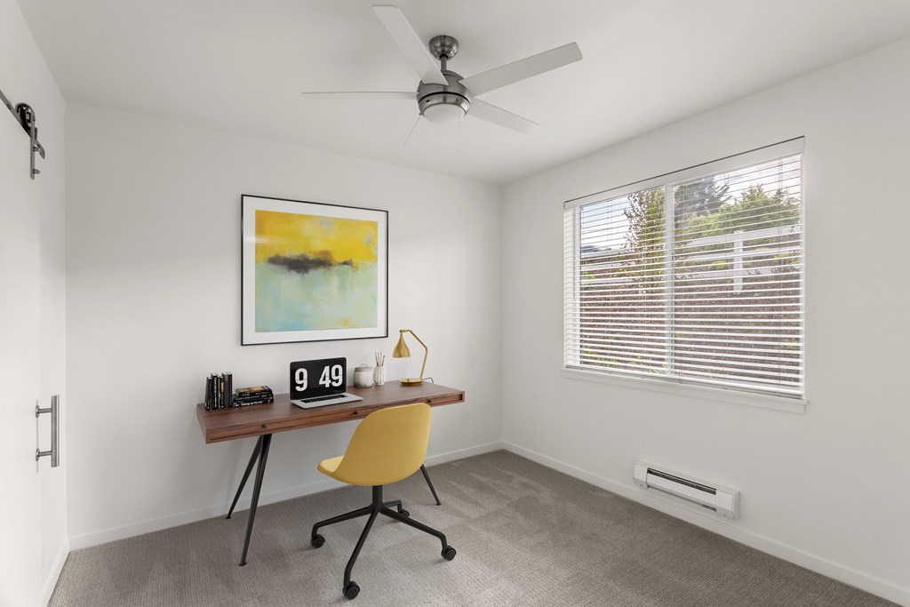 A room with a yellow chair and a painting on the wall.