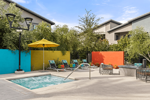 A pool area with a yellow umbrella and blue water.