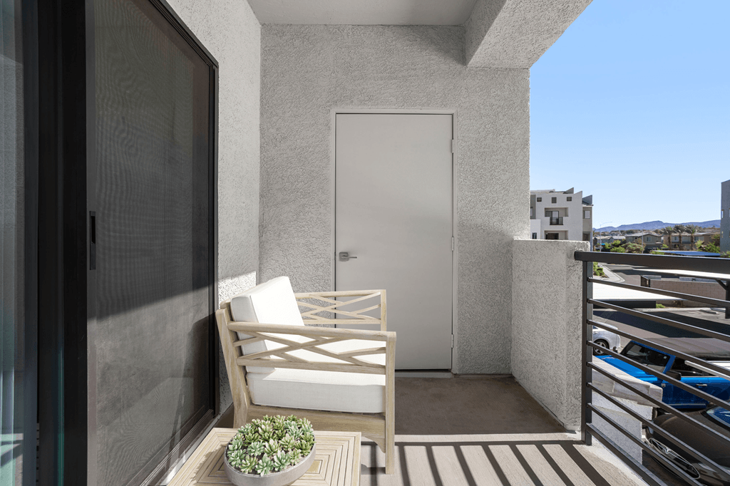 A balcony with a white chair and a potted plant.