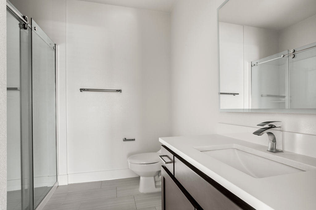 A white bathroom with a toilet, sink, and mirror.