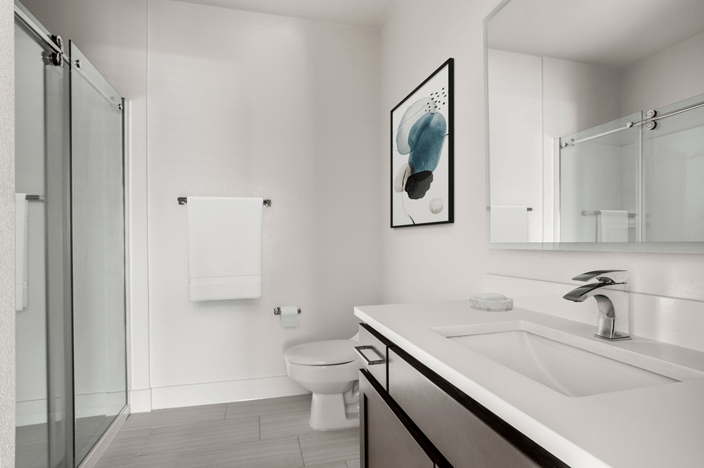 A modern bathroom with a toilet, sink, and mirror.