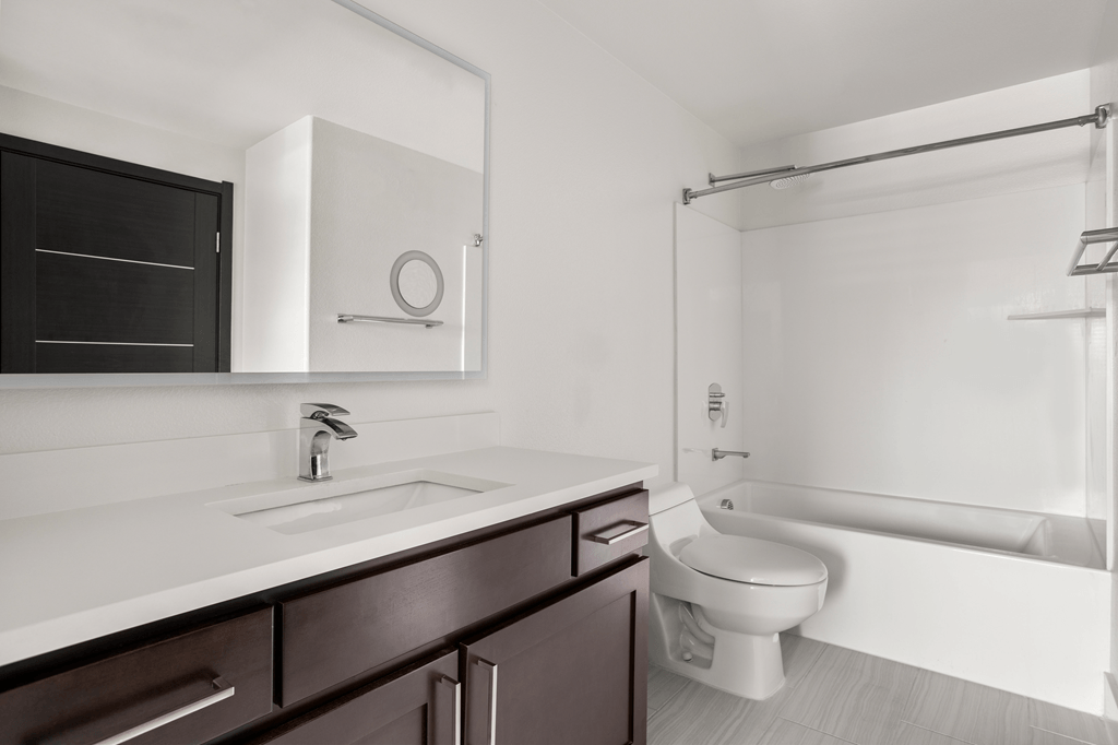 A white sink is on a countertop next to a toilet.