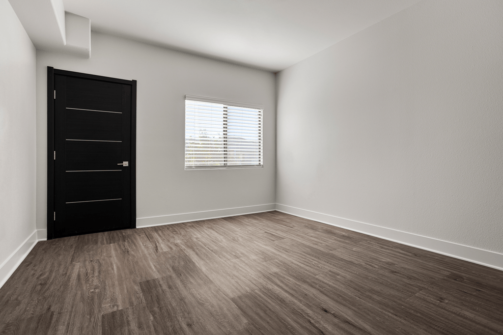 A room with a black door and a window with blinds.