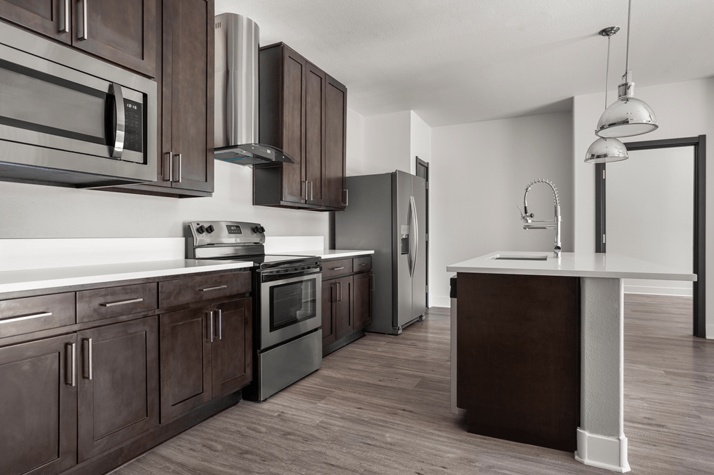 A modern kitchen with dark brown cabinets and stainless steel appliances.