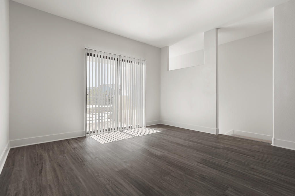 A room with a window and wooden flooring.
