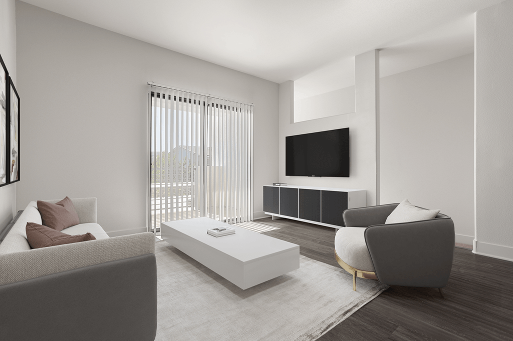 A modern living room with a grey couch, a white coffee table, and a flat screen TV mounted on the wall.