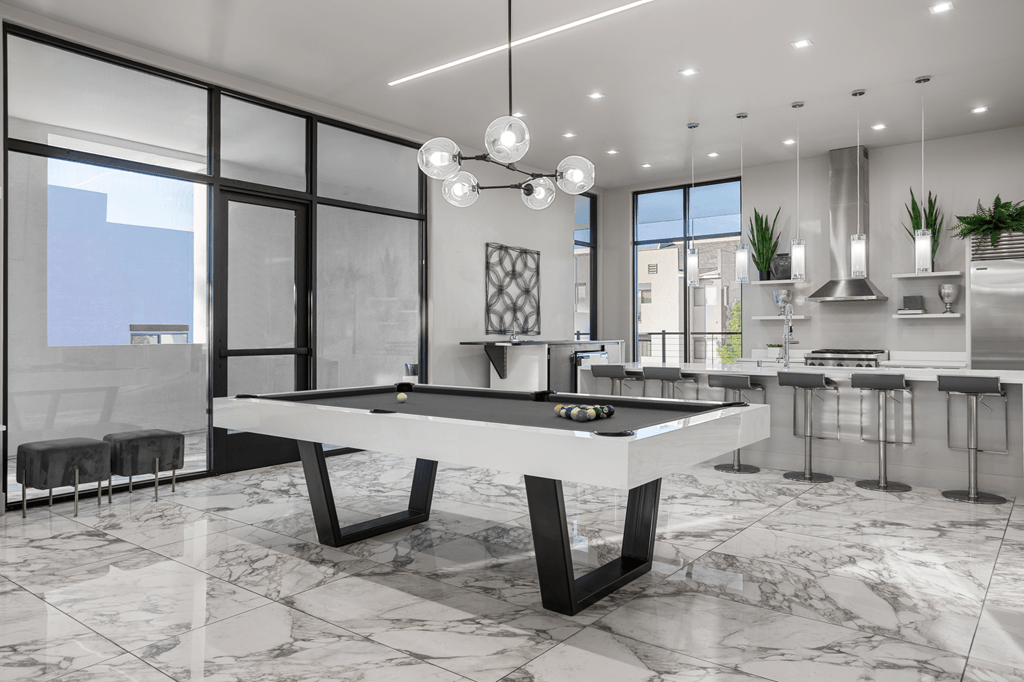 A modern kitchen with a pool table in the middle.