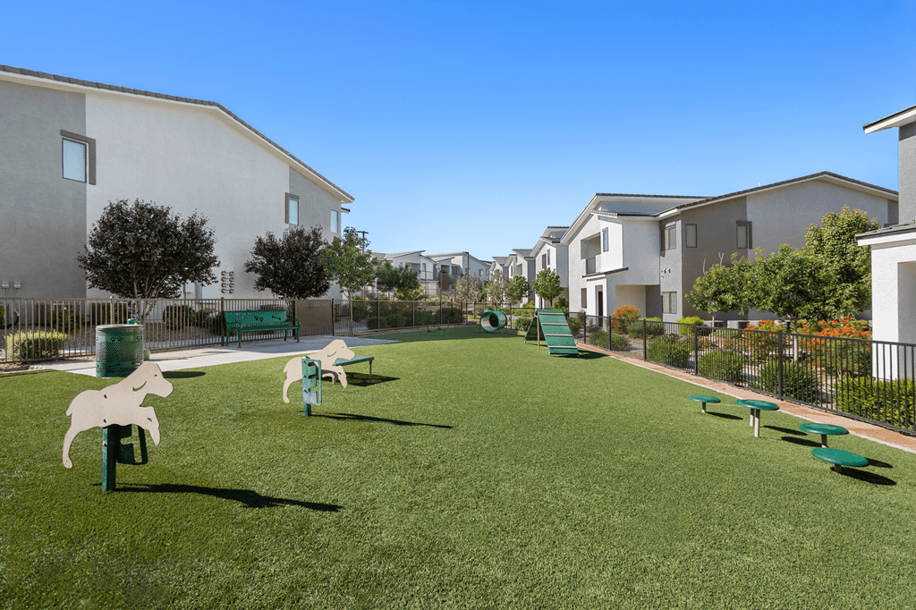 A playground with a white horse statue and green benches in front of apartment buildings.