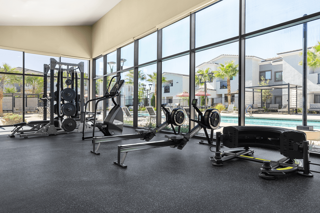 A gym with a view of a pool and houses.