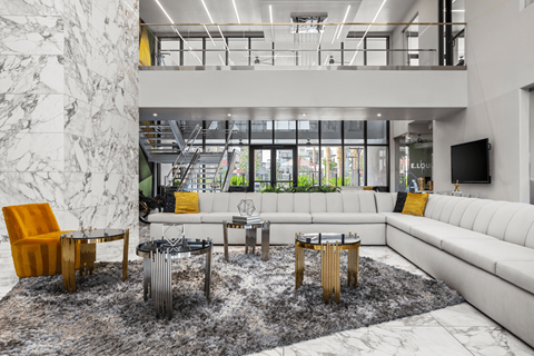 A living room with a white sofa, a yellow chair, and a coffee table with a metal base.