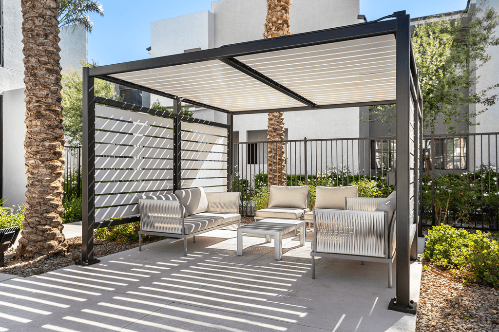 A patio with a white couch and a black metal fence.