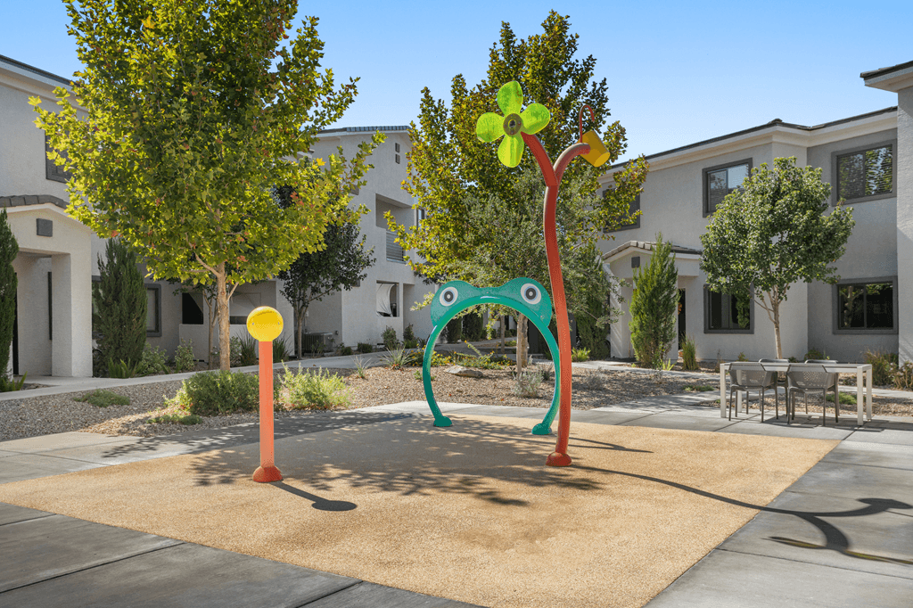 A playground with a green frog and a red and orange pole.