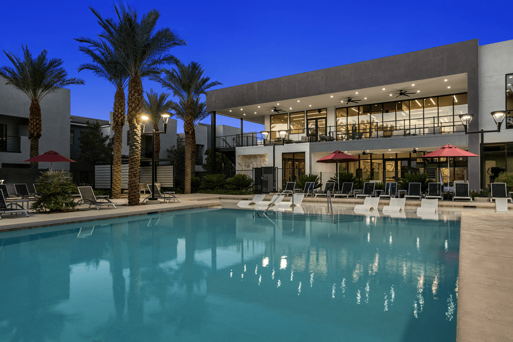 A swimming pool is surrounded by palm trees and lounge chairs.