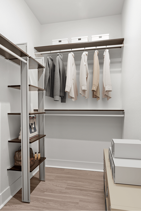 A walk in closet with clothes hanging and shelves.