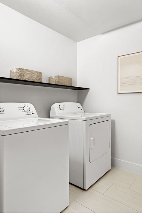 Two white washing machines in a laundry room.