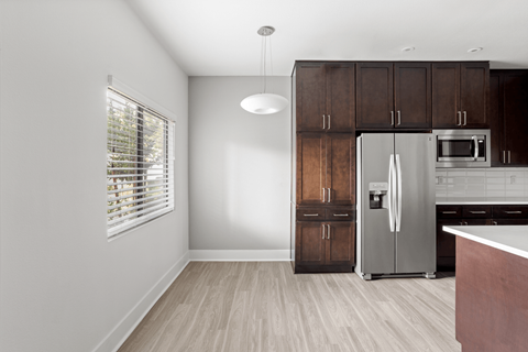 A kitchen with a refrigerator, microwave, and oven.