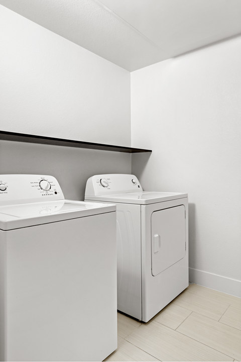 Two white washing machines in a laundry room.