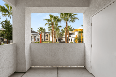 A white room with a view of a street with palm trees.