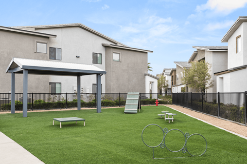 A park area with a playground and a picnic table in front of apartment buildings.