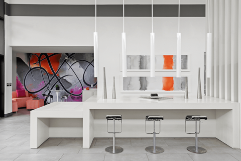 A white bar with three stools in front of a wall with a mural.