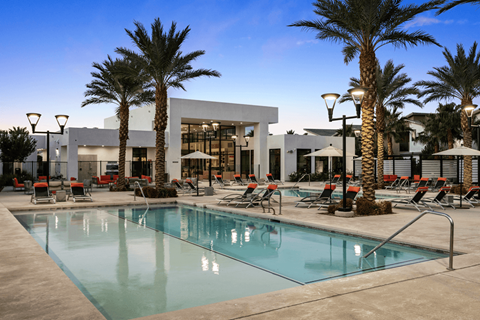 A pool surrounded by palm trees and lounge chairs.
