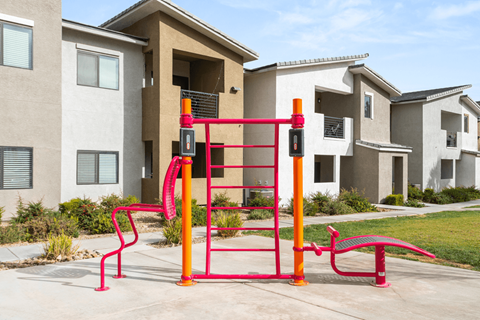 A red and orange playground structure in front of a building.