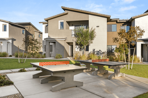 A concrete table is in the middle of a concrete patio.