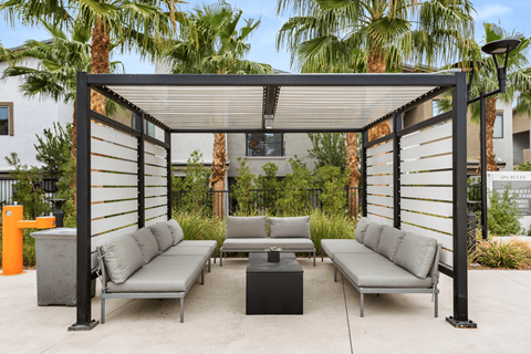 A patio with a black metal frame and grey cushions.