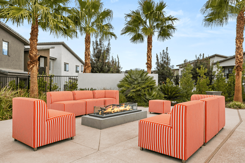 A patio with a fire pit and striped couches.