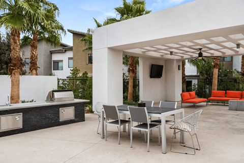 A patio with a table and chairs under a white pergola.