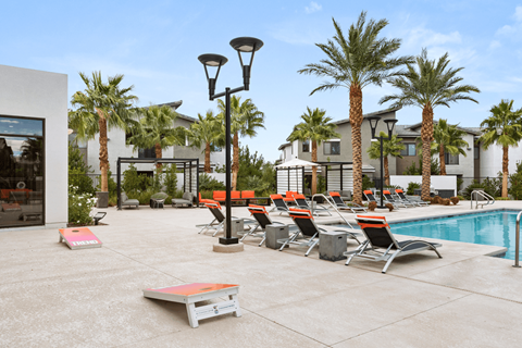A poolside area with lounge chairs and palm trees.