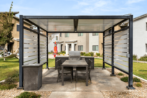 A patio with a table and chairs is covered by a roof.