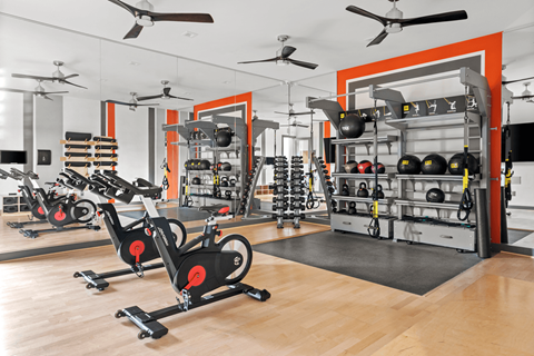 A gym with exercise bikes and a rack of kettlebells.