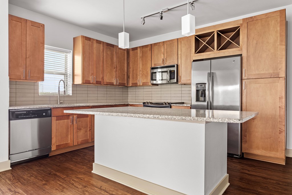 A kitchen with wooden cabinets and a white island.