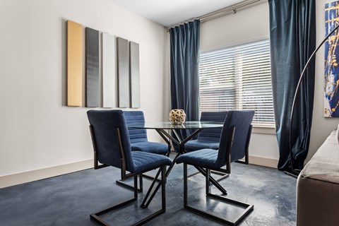 A dining room with a glass table and blue chairs.