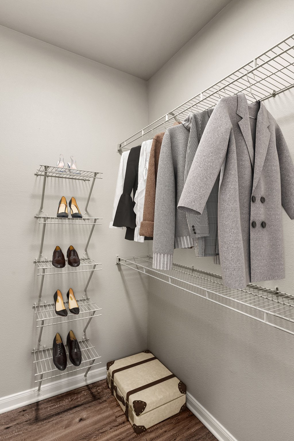 A closet with a coat hanging on a rod and a shelf with shoes.