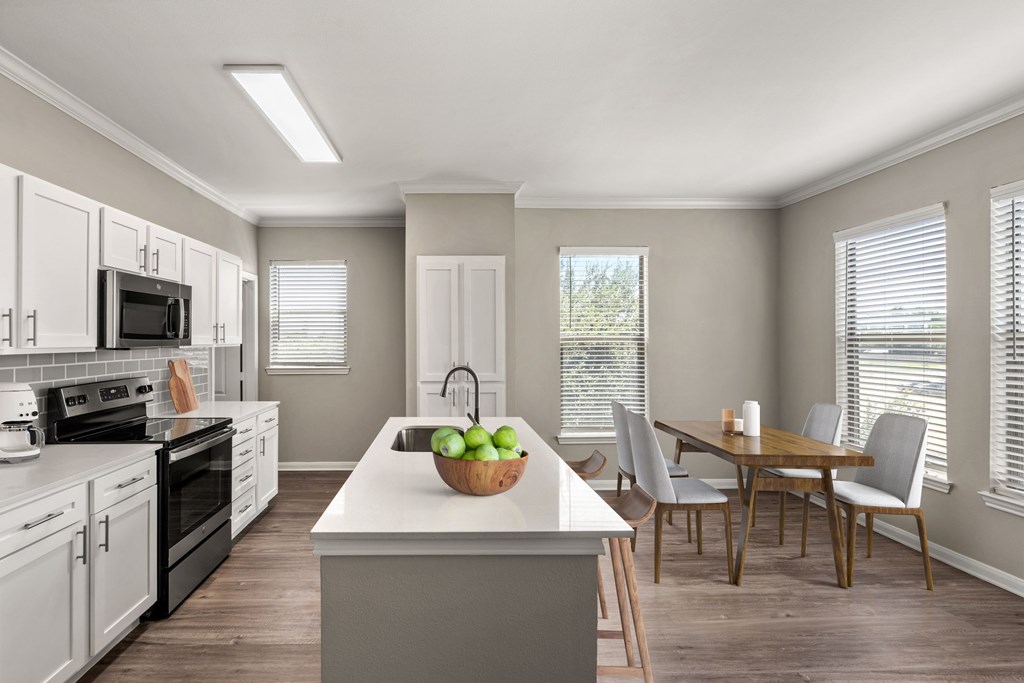 A kitchen with a white countertop and a bowl of green apples on it.