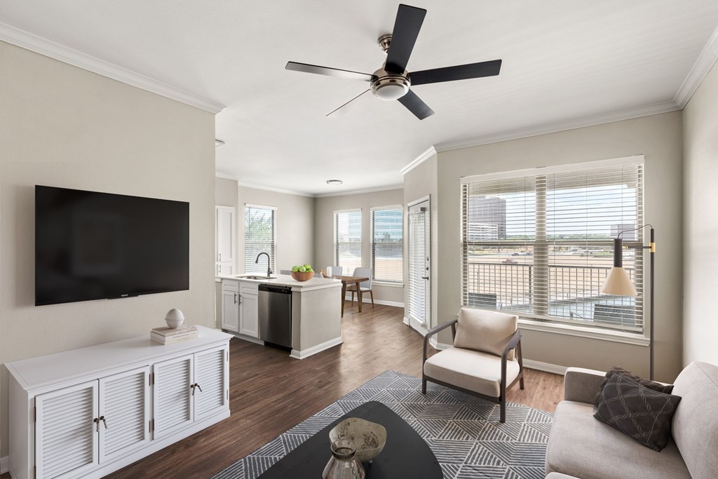 A living room with a television, a couch, and a ceiling fan.
